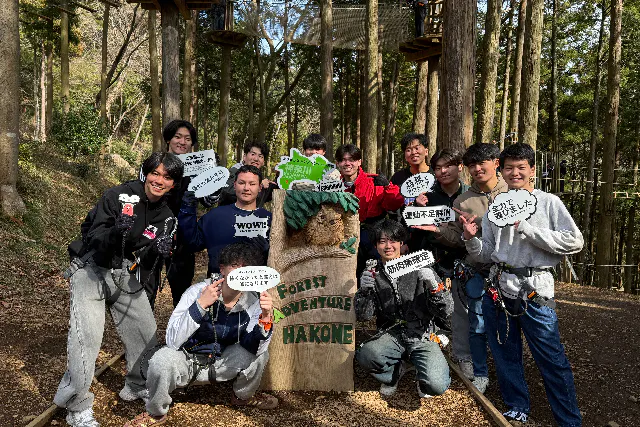 フォレストアドベンチャー箱根の看板の前で記念撮影する参加者グループ